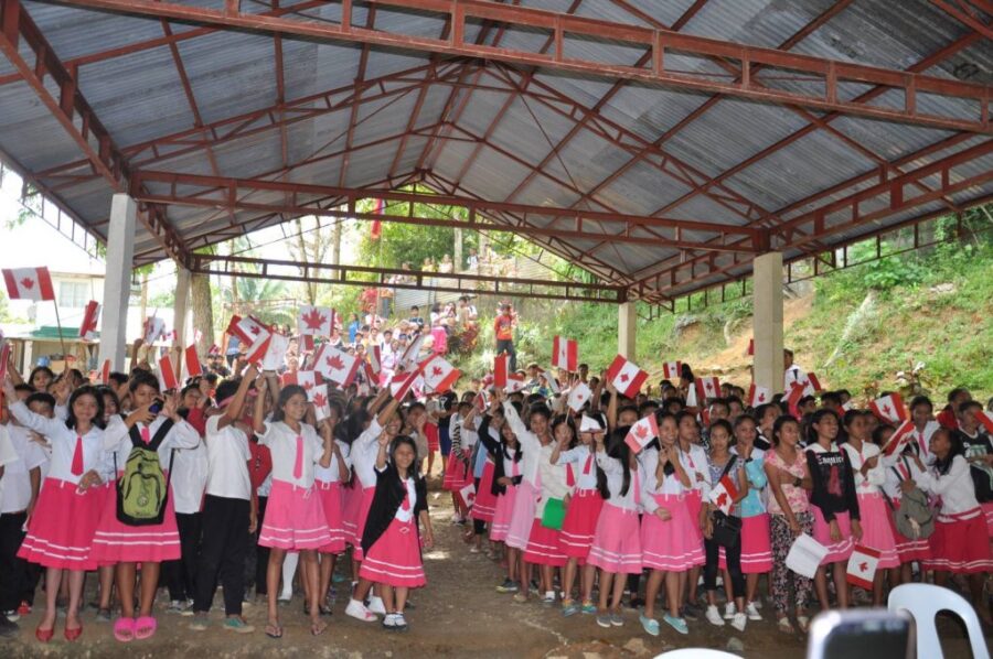 School children in Philippines waving small Canada flags