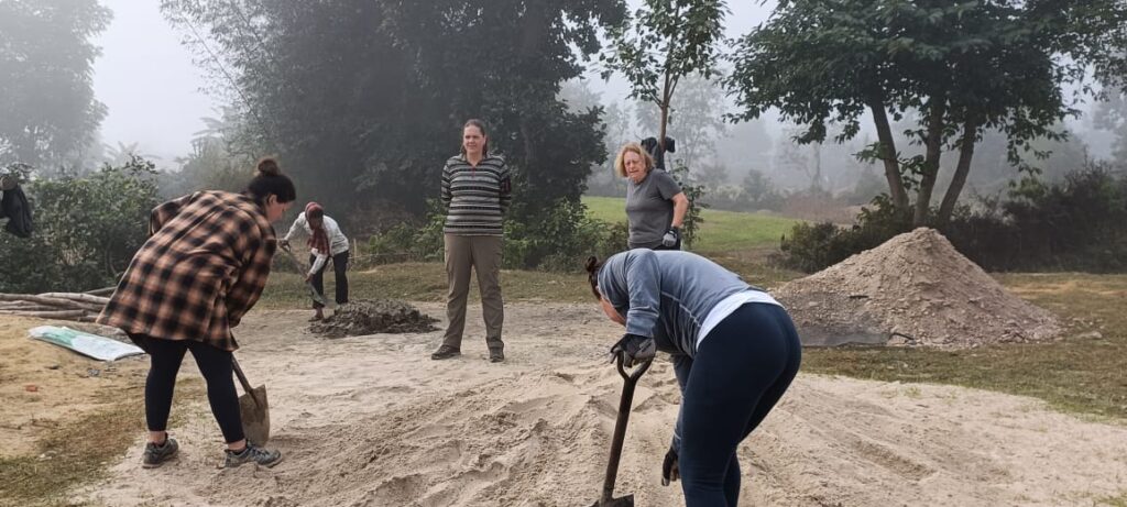 DWC volunteers digging in sand pile Nepal