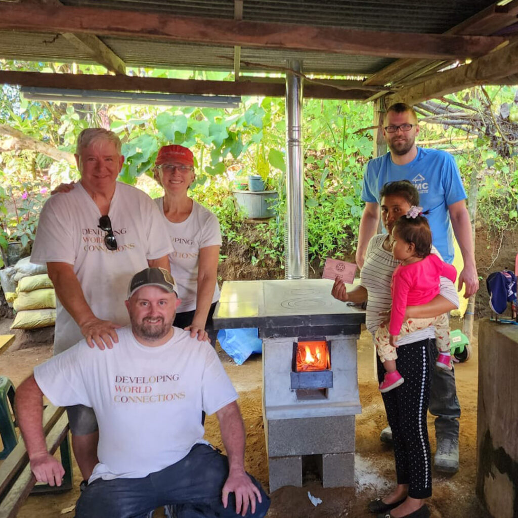 DWC Rotary volunteers around lit, newly installed Eco stove