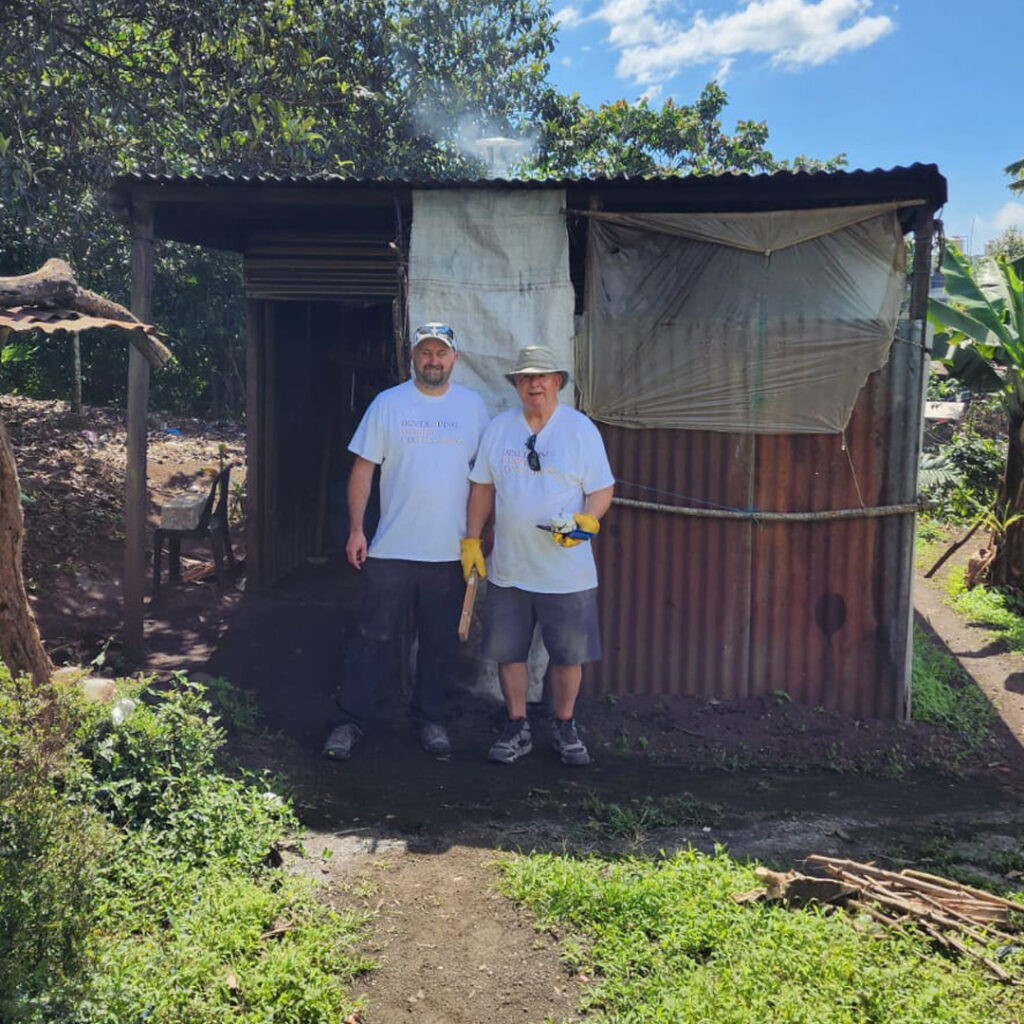 Volunteers at doorway of tin home in Guatemala