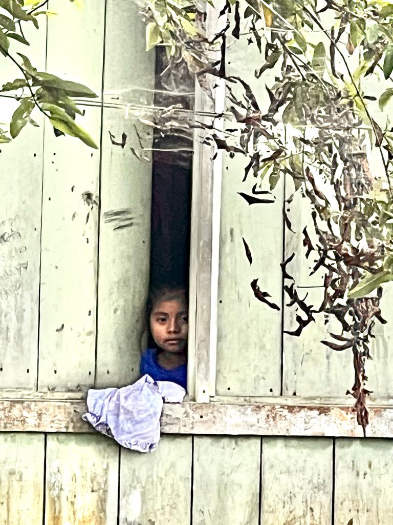Child peeking through wood window slat Costa Rica