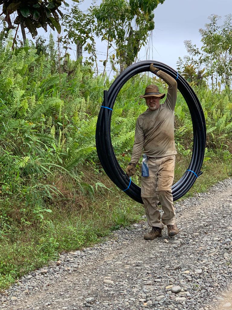 DWC volunteer in Costa Rica carrying PVC pipe