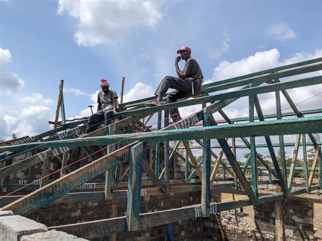 Local workers sitting on roof trusses on DWC project in Kenya