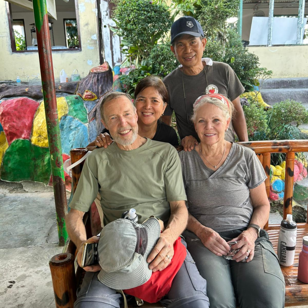 DWC volunteers sitting on bench with locals standing behind them Philippines