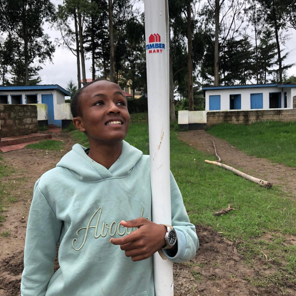 Local school kid holding Timber Mart pole Kenya