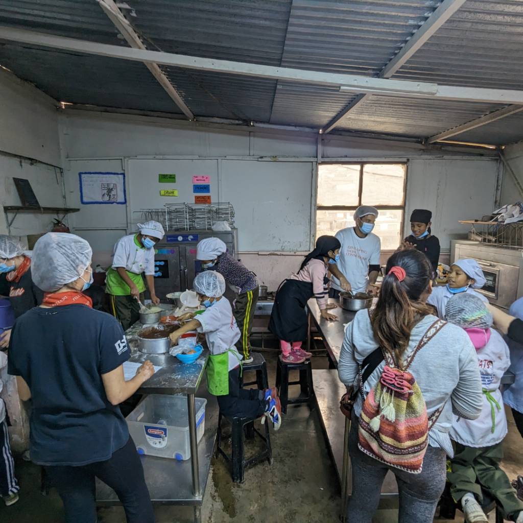 School kids and volunteers in pastry kitchen in San José Obrero School Peru