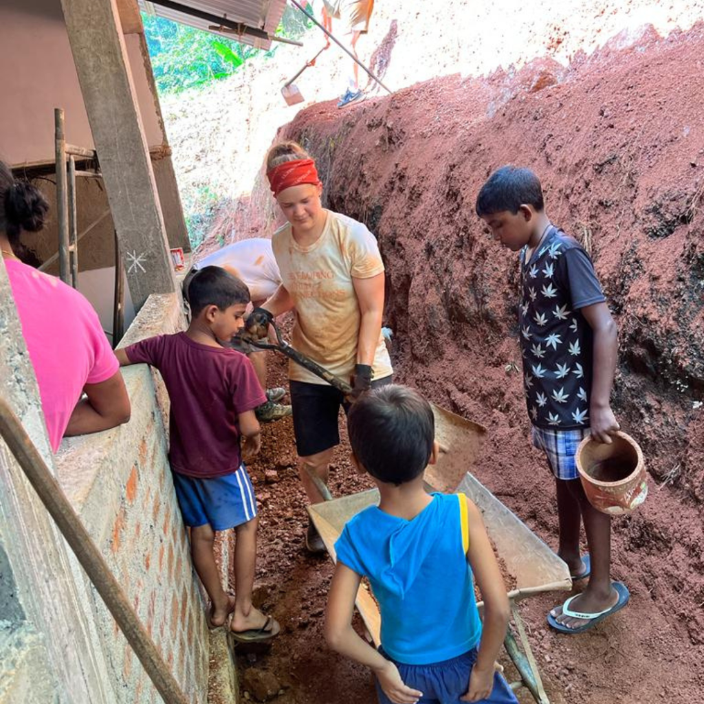 Volunteer with wheelbarrow and shovel with local kids Sri Lanka
