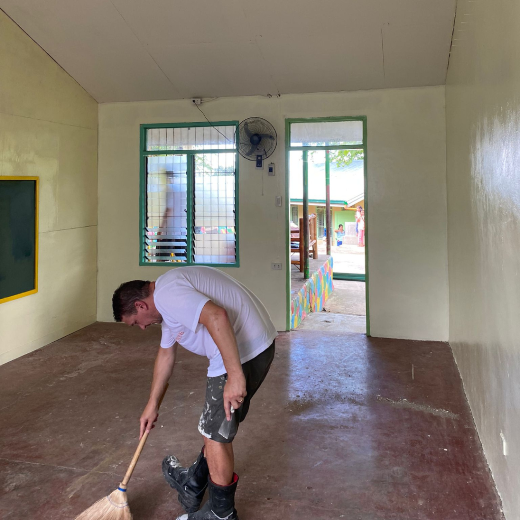 Volunteer sweeping floor of classroom Philippines