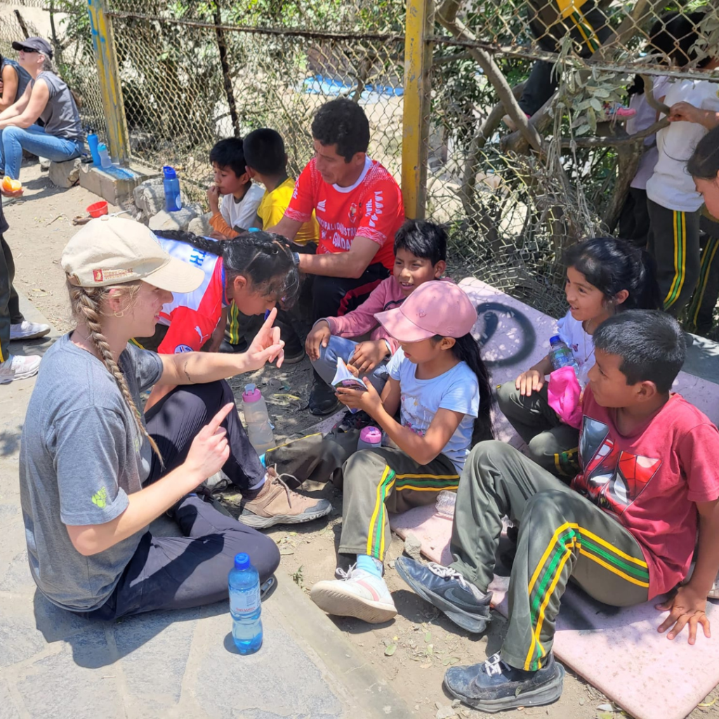 Urban Systems volunteers sitting outside with schoolchildren Villa María del Triumfo Peru