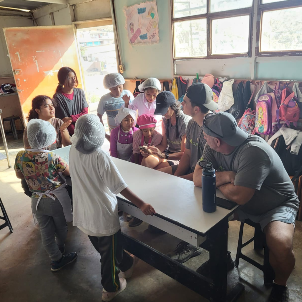 Urban Systems volunteers sitting with students in pastry shop San José Obrero School