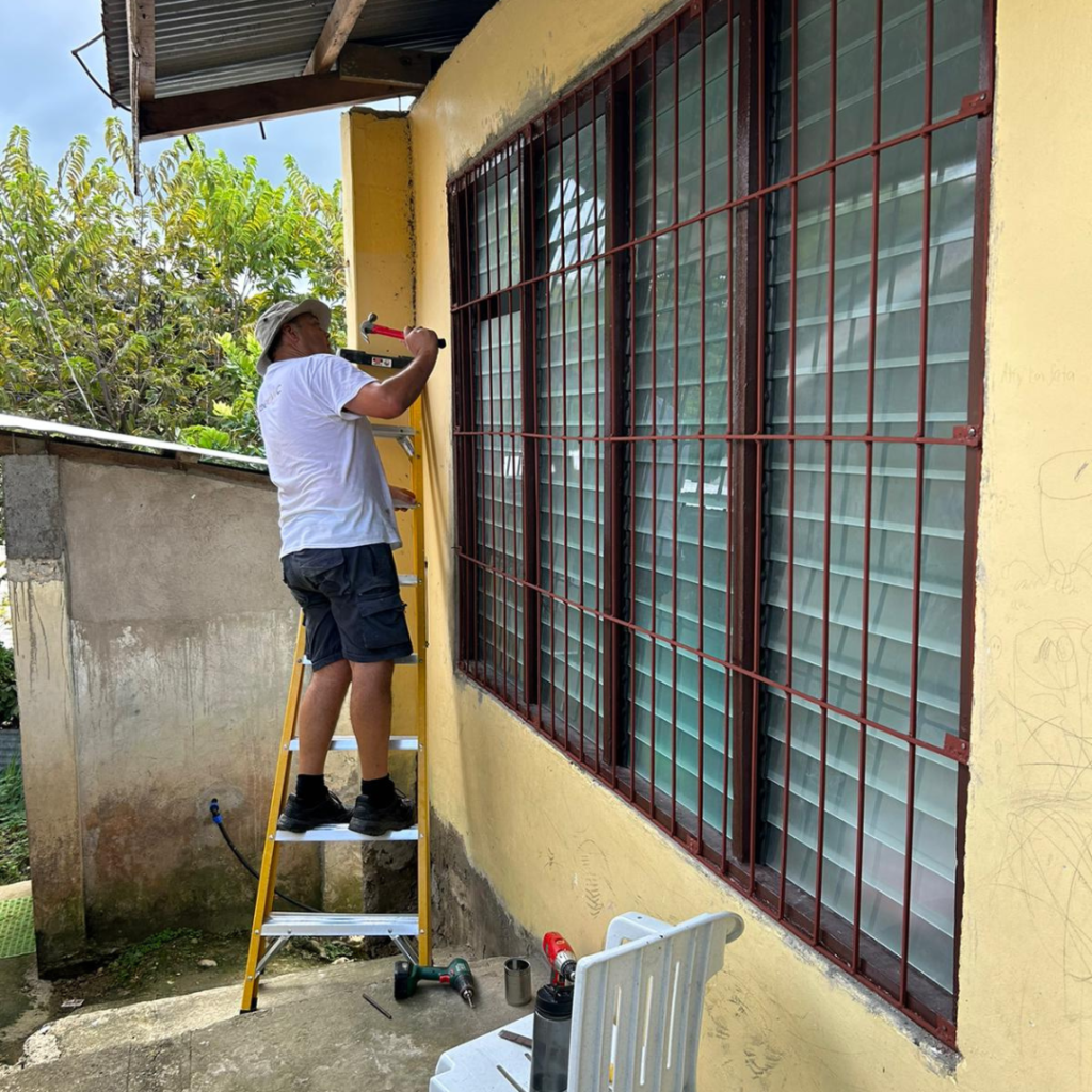 Volunteer installing window of classroom door Philippines