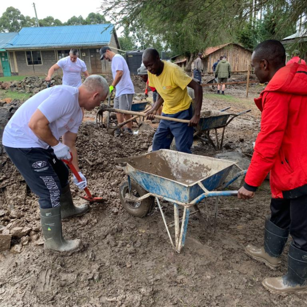 DWC volunteers and locals shoveling mud into wheelbarrows Kenya