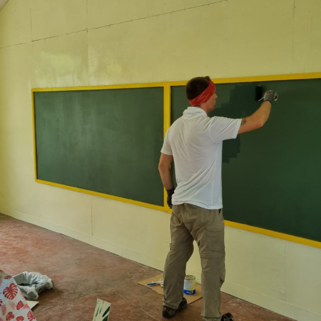 Volunteer painting blackboard in classroom project Philippines