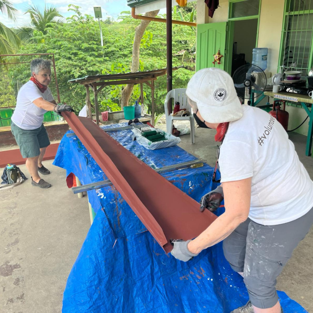 DWC volunteers in Philippines painting soffit covers