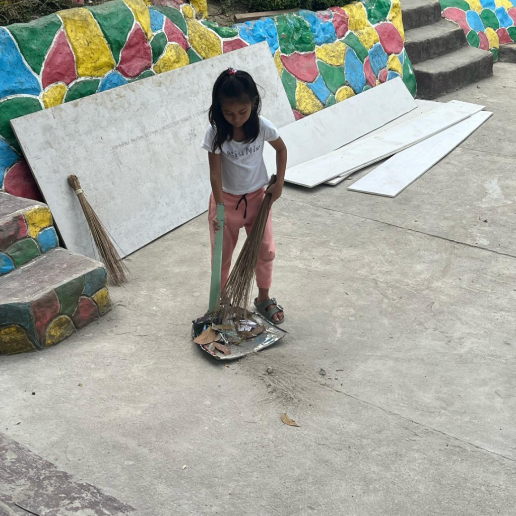 Young girl sweeping up construction debris Philippines