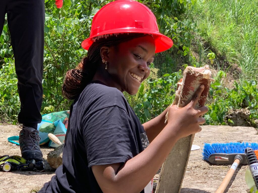 Volunteer wearing hard hat in hole holding a level Costa Rica