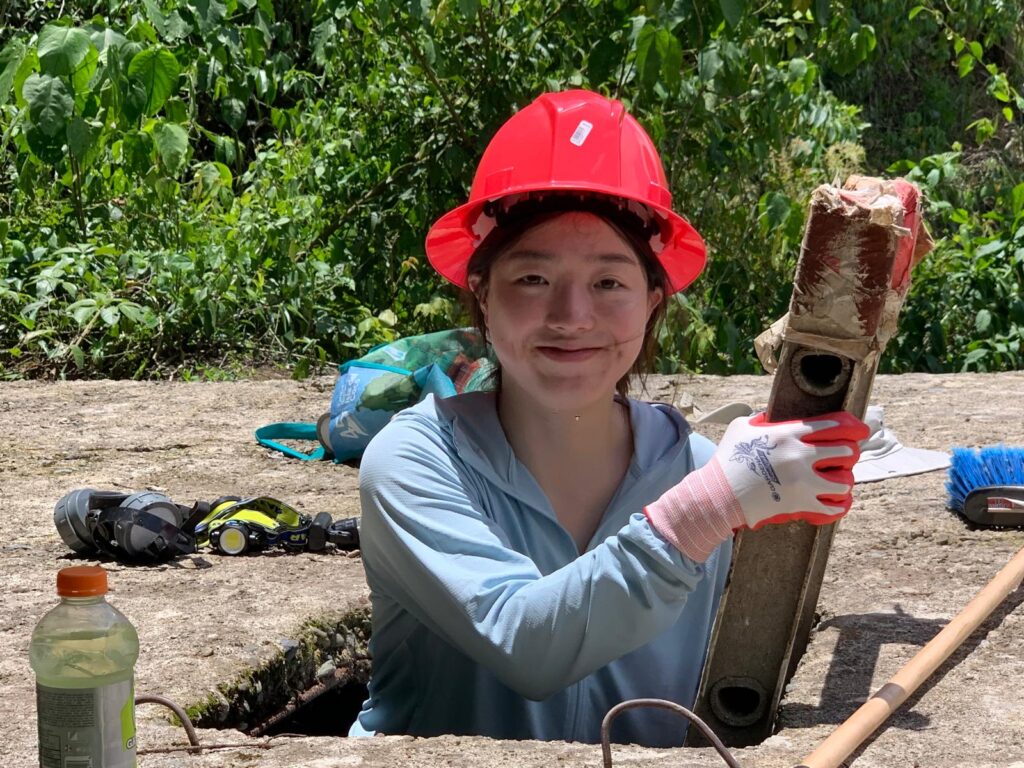 Volunteer wearing hard hat in hole holding a level Costa Rica