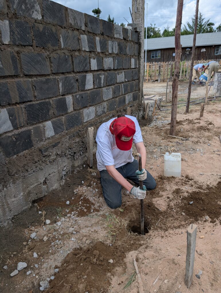 Volunteer Digging hole outside wall Kenya
