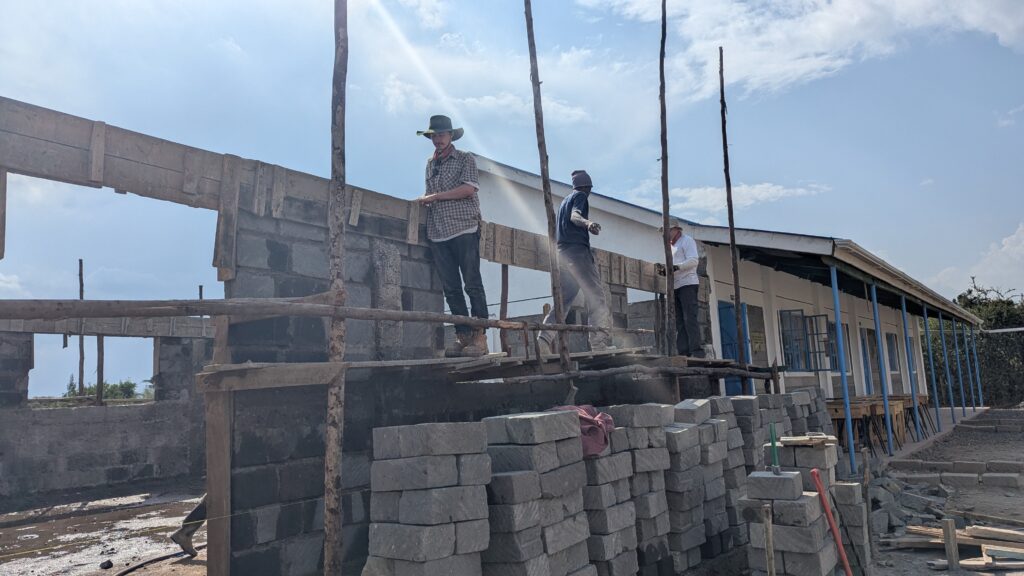 Volunteers and local tradespeople standing on scaffolding Kenya