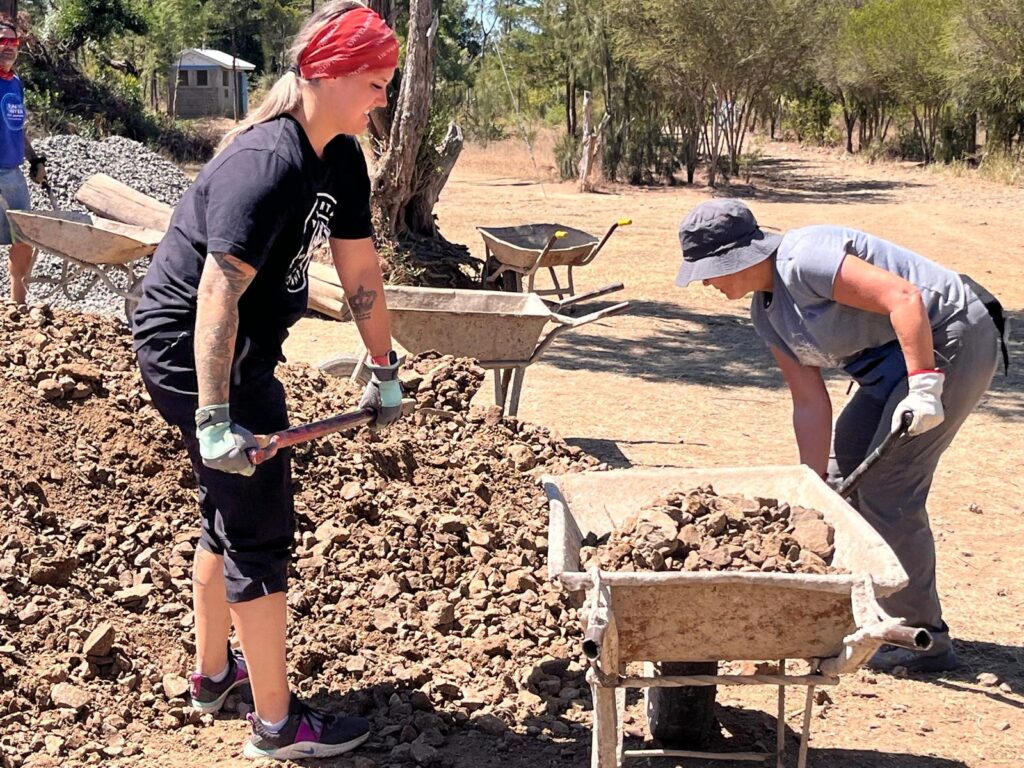 Volunteers shoveling dirt into wheelbarrow Kenya