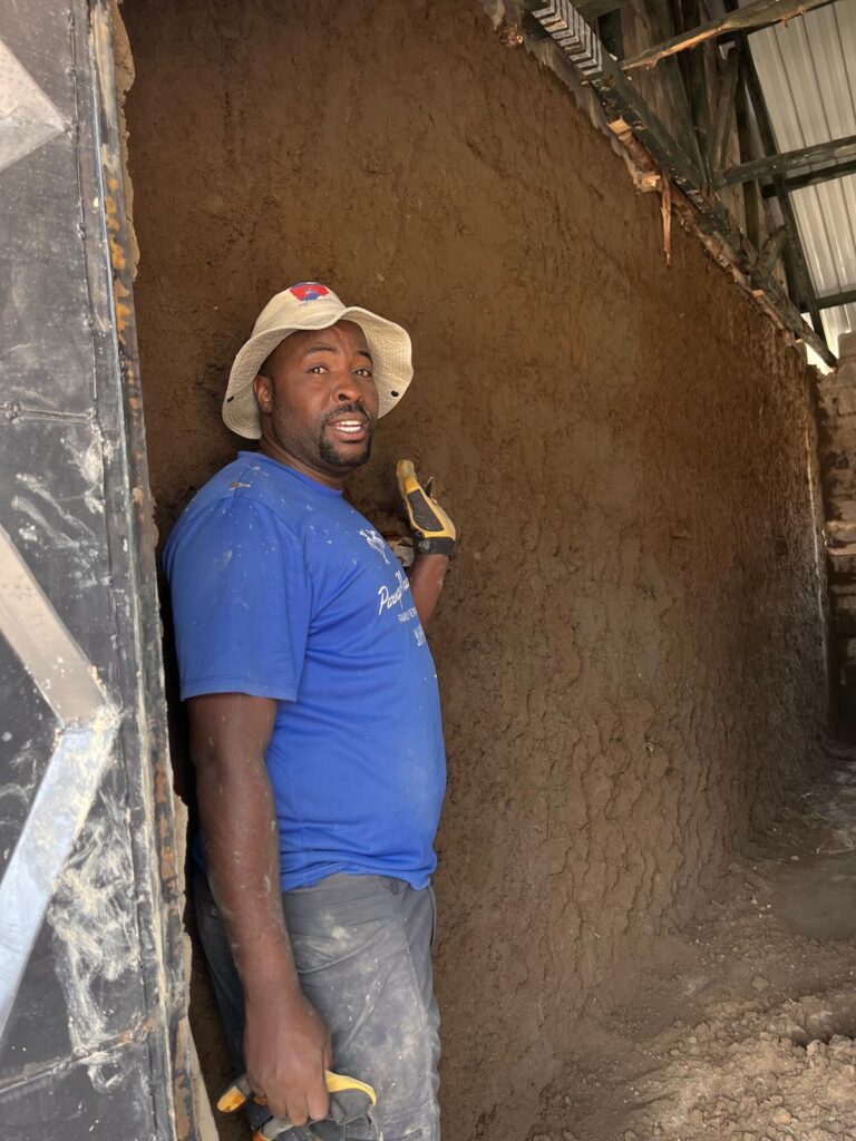 Local worker smoothing mud walls at project site Kenya