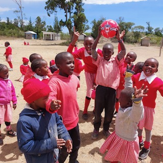 School kids playing with ball outside Kenya