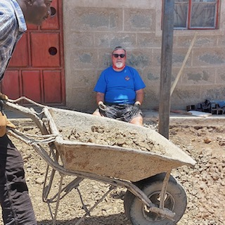 Volunteer with wheelbarrow full of dirt Kenya