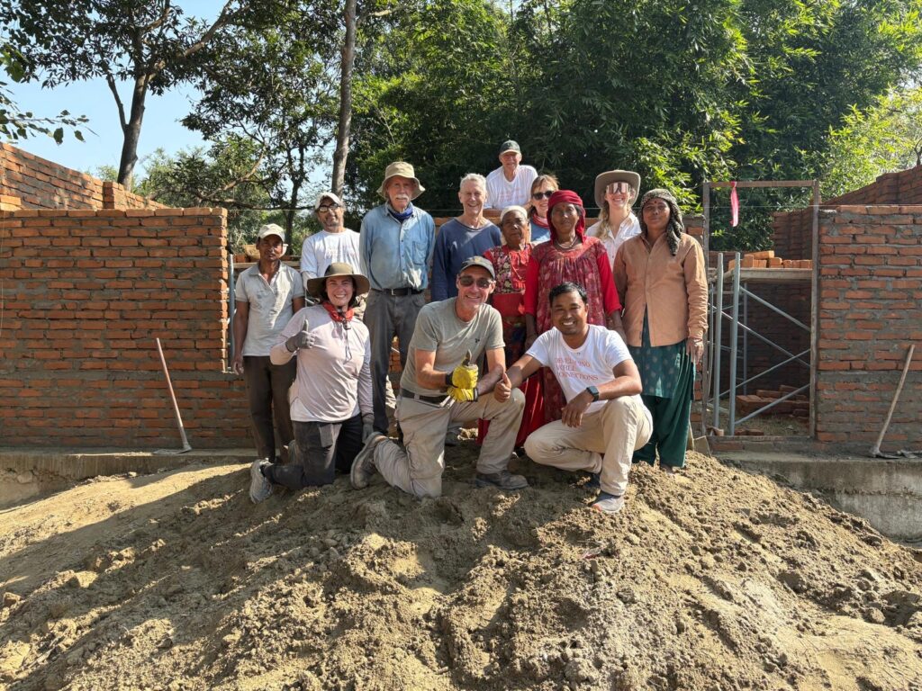 Volunteers posing on sand pile at project site Nepal