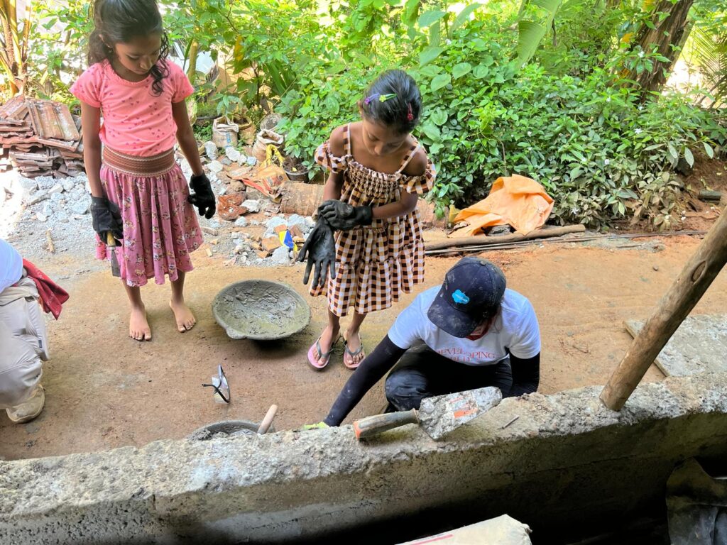 Volunteer working on project with children onlookers Sri Lanka